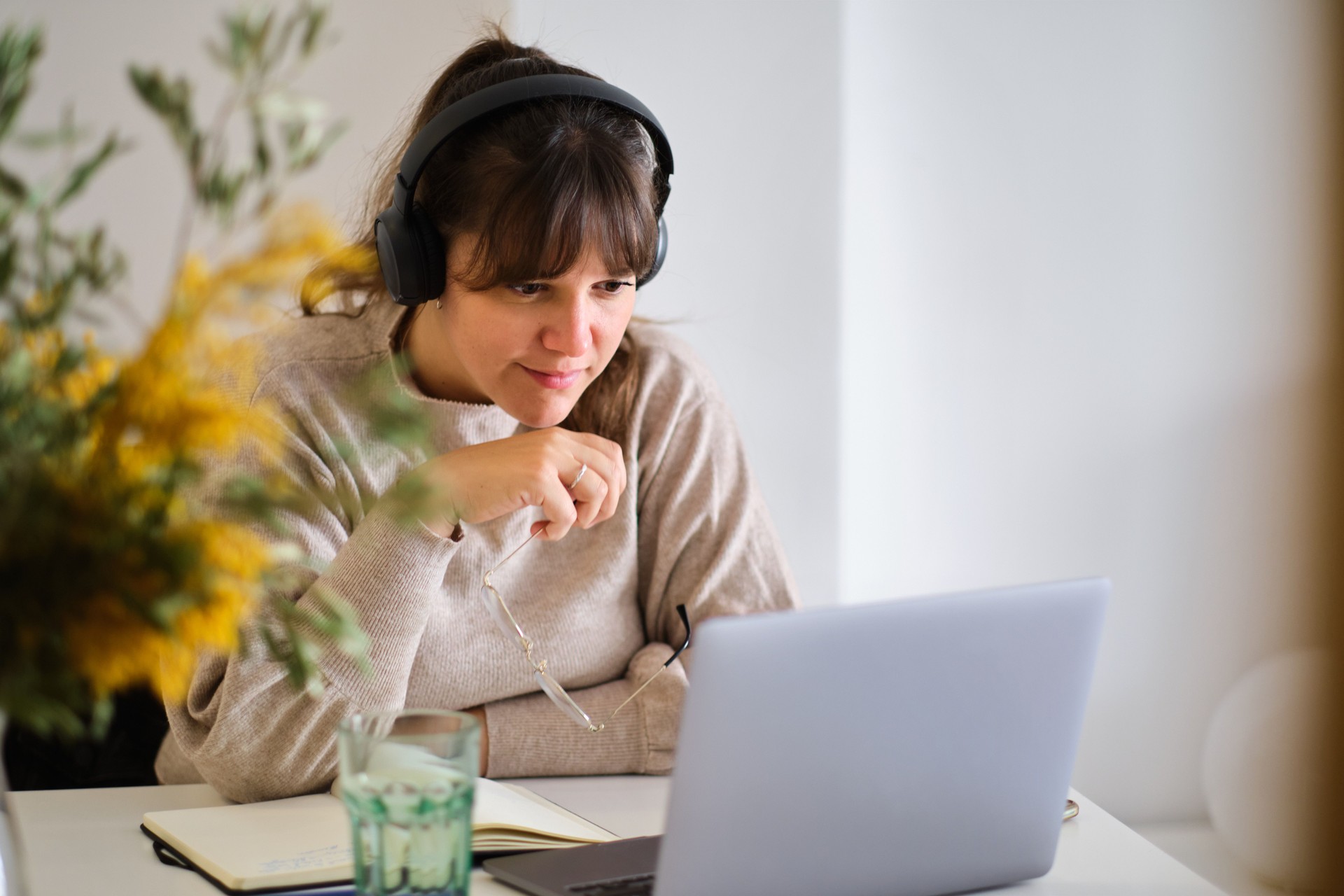 front view portrait of a young female doing a video call meeting with a laptop and headphones indoors